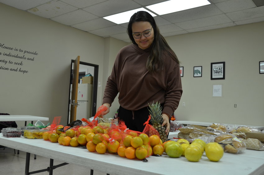 Wesley House Building Health Program Manager Audrey Ricks arranges fruit on the table for people to select from as part of the food pantry program on Wednesday at the Wesley House.