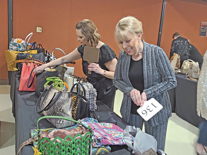 Ashlee Ricks, left, and Pam Gebhardt inspect the purses that would be featured during the live auction at the &ldquo;Bags to Riches&rdquo; Safehouse Crisis Center fundraiser on Tuesday night.