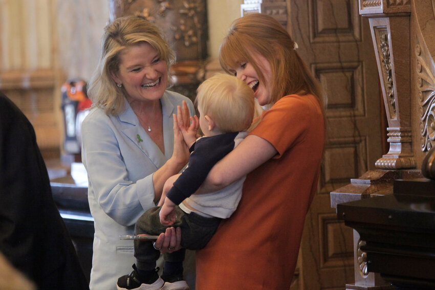 Kansas state Sen. Cindy Holscher, left, D-Overland Park, gives a high-five to Leland, the young son of Sen. Kristen O'Shea, right, R-Topeka, during a session of the Senate, Wednesday, March 29, 2023, at the Statehouse in Topeka, Kan. Lawmakers are preparing for an intense four days of work ahead of their annual &quot;Drop Dead Day&quot; deadline. (AP Photo/John Hanna)