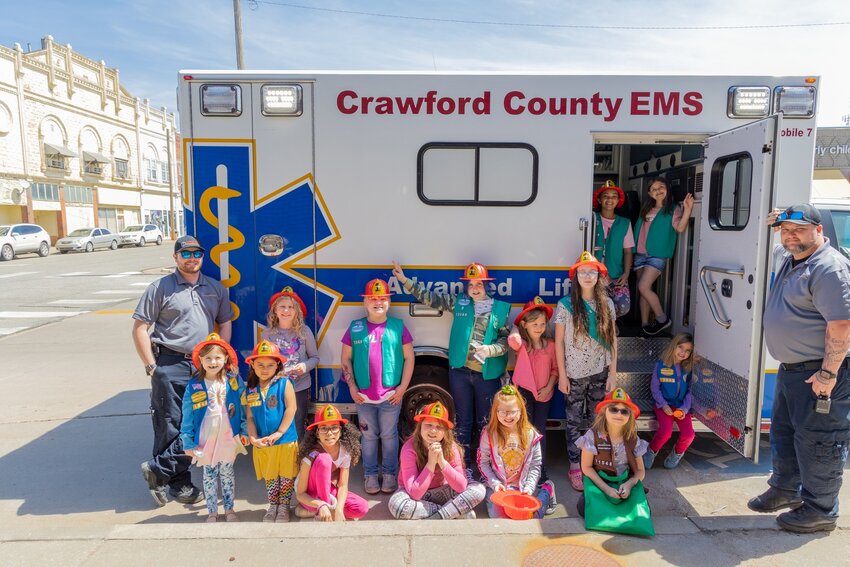 Members of Girl Scout Troop 71548 pose with EMTs and paramedics of the Crawford County Emergency Medical Service on Friday. The scouts were earning their Democracy badges.