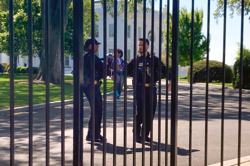 U.S. Secret Service uniformed division police officers carry a young child who crawled through the White House fence on Pennsylvania Avenue in Washington, Tuesday, April 18, 2023. The toddler earned the title of one of the tiniest White House intruders after he squeezed through the metal fencing on the north side of the executive mansion. Officers walked across the North Lawn to retrieve the child and reunite him with his parents on Pennsylvania Avenue. (AP Photo/Nancy Benac)