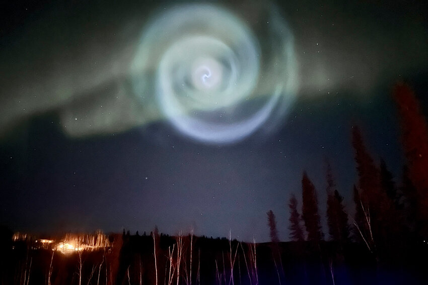 In this photo provided by Christopher Hayden, a light baby blue spiral resembling a galaxy appears amid the aurora for a few minutes in the Alaska skies near Fairbanks, Saturday, April 15, 2023.  The spiral was formed when excess fuel that had been released from a SpaceX rocket that launched from California about three hours earlier turned to ice, and then the water vapor reflected the sunlight in the upper atmosphere. (Christopher Hayden via AP)