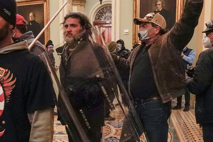 FILE - Rioters, including Dominic Pezzola, center with police shield, are confronted by U.S. Capitol Police officers outside the Senate Chamber inside the Capitol, Wednesday, Jan. 6, 2021, in Washington. A federal jury is scheduled to hear a second day of attorneys&acirc; closing arguments in the landmark trial for former Proud Boys extremist group leaders charged with plotting to violently stop the transfer of presidential power after the 2020 election.(AP Photo/Manuel Balce Ceneta, File)