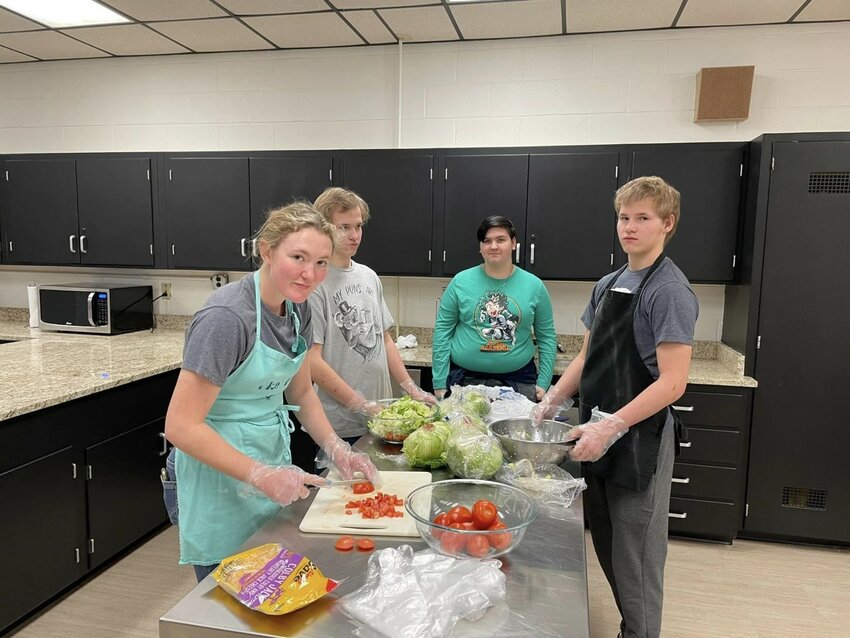 Southeast FACS students prepare ingredients on their stainless-steel prep table. In the background, Vratil decided to keep the old cabinets, but decided to repaint them and polish the handles and hinges to look like brand-new hardware.