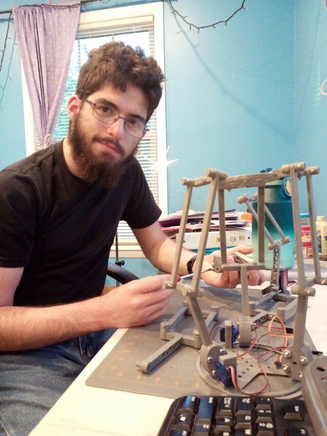 Riachi working on Delta Robot with three degrees of freedom, much like an arm, that he designed and 3-D printed. It is controlled by servos wired to an Arduino board and writing a program for it.