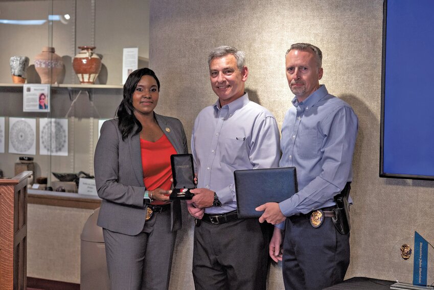 Sgt. Detective LaMour Romine (left) and Chief of Police Brent Narges (right) present the department&rsquo;s Meritorious Service Medal to Detective John Harrison (center) during his retirement ceremony held Tuesday, May 30.