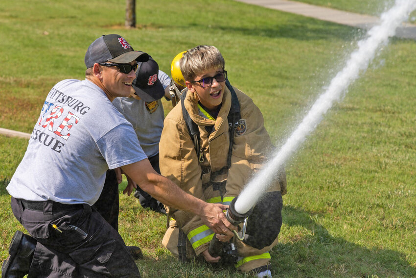 Andrew Johnston (left) and Tanner Orth (center) teach a student from the PHS Leadership Academy how to properly use a firehose.
