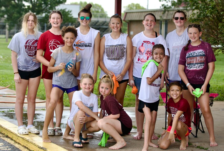 Northeast Junior High cheerleaders take a break after washing several cars on Friday. The reintroduced middle school cheer team, which includes 11 members, held the car wash in the afternoon in the Northeast High School parking lot to raise money for the team.