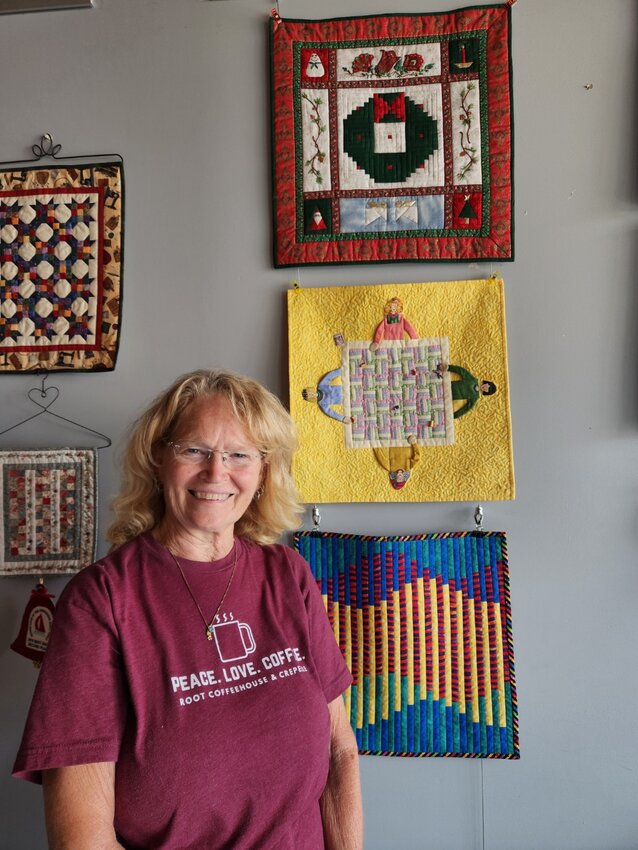 Debbie Hurt Walker stands in front of a display of her quilts at Root Coffeehouse in Pittsburg.