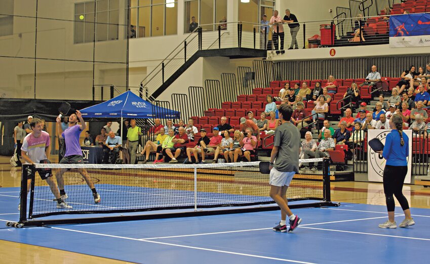 J.W. Johnson, second from left in purple, prepares to deliver a serve during an exhibition match at John Lance Arena on Monday during the Johnson Family Pro Pickleball Day as the crowd watched J.W. and Dylan Frazier battle against Jorja Johnson and Gabriel Tardio.