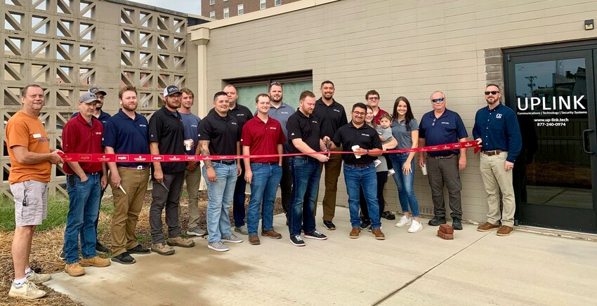Uplink employees along with local business and chamber members prepare to cut the ribbon at Friday&rsquo;s ceremony, located at 320 N. Locust St.