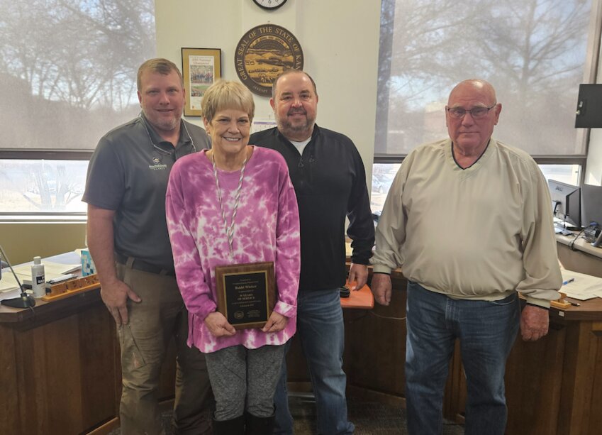 Deputy County Clerk Bobbi Wicker, posing with County Commissioners (left to right) Bruce Blair, Tom Moody, and Carl Wood, celebrates 35 years with the county.