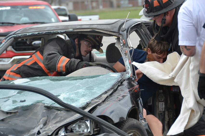 Arma firefighters extract the &ldquo;deceased&rdquo; driver of one of the vehicles during a simulated car crash at Northeast High School in Arma. The simulation was sponsored by the SAFE Club, stressing the importance of seatbelts and not driving while distracted.