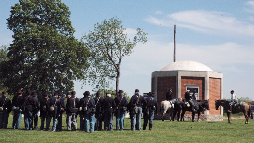 A Union infantry company forms up near the magazine at the Fort Scott National Historic Site while a section of cavalry troopers allow their horses to graze.