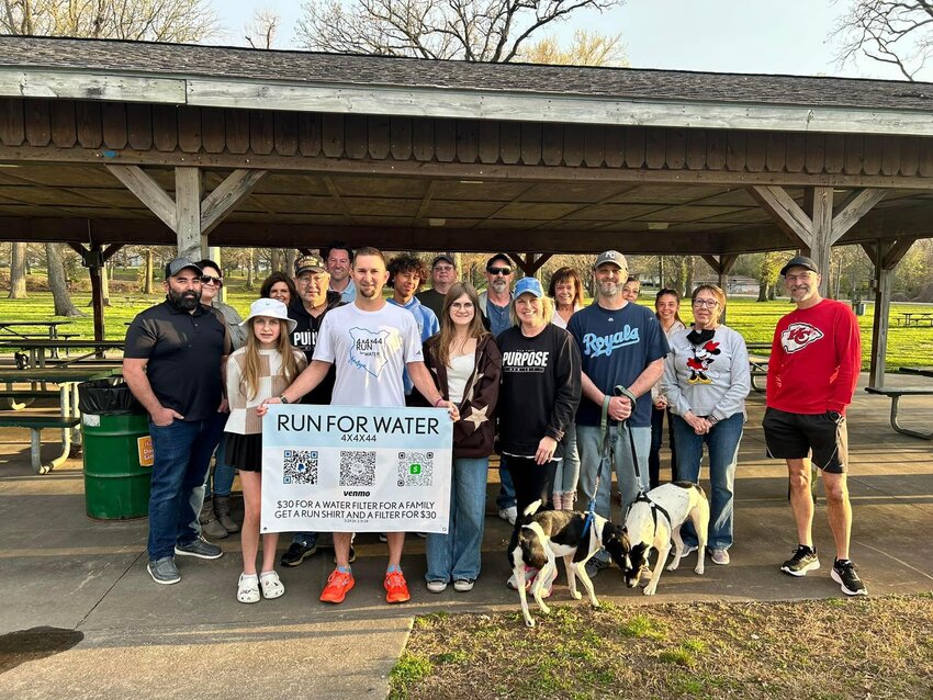 Eric Gudde, holding sign, stands with family, friends and community members following the completion of his first route as the local teacher ran 44 miles in 44 hours as part of an effort to fund and provide a water well with clean water for a village in Kenya.