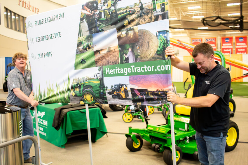 Tommy Thompson, left, and Joey Wyatt set up signage for the Heritage Tractor exhibit in the Plaster Center at Pittsburg State University, Tuesday. They will be joined over the next few days by a wide range of exhibitors in preparation for the 49th annual Four-State Farm Show, which begins on Friday. Hours are 8 a.m. to 4 p.m. on Friday and Saturday and from 8 a.m. until 3 p.m. on Sunday. Admission is free and parking is available in the Brown Parking lot east of Carnie Smith Stadium or at the Kansas Technology. Free shuttle buses and trams will operate each day.