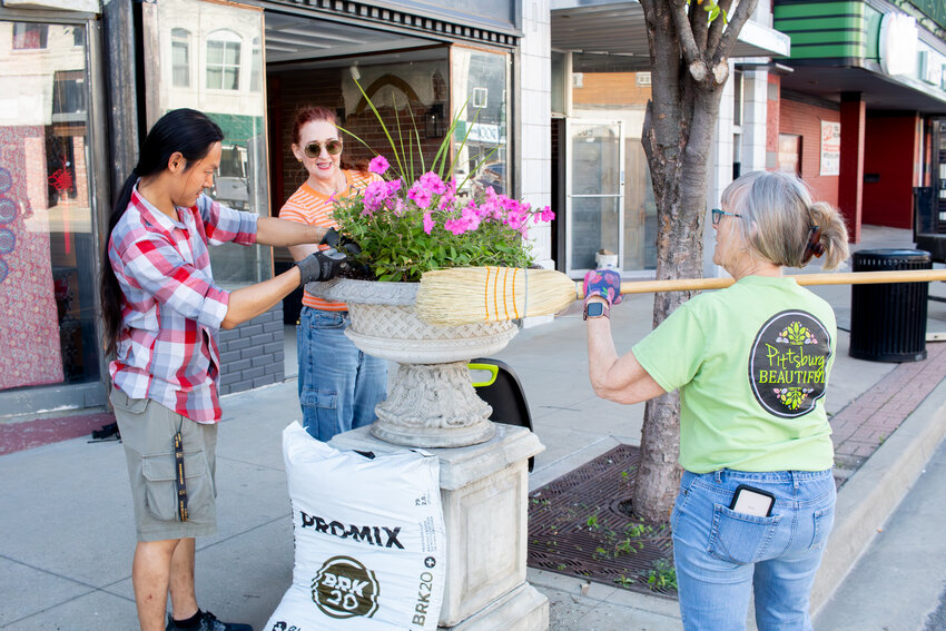 Pittsburg Beautiful members David Su, left, Stephanie Watts, center, and Nancy Brewer, plant petunias in one of the 36 urns that grace downtown Pittsburg, Tuesday. Other members of the group performed a similar service up and down the street, which is graced not only by the urns, but also by hanging baskets, which will be watered daily during the summer.
