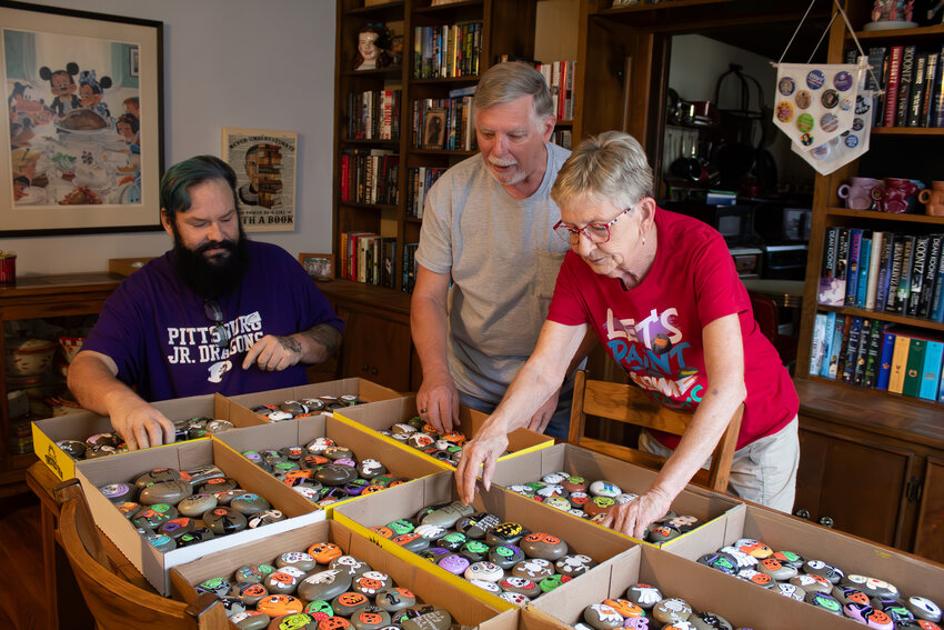 From left, Kyle Million, Jim Hill and Kathy Thompson sort 350 Halloween-themed painted rocks in Thompson&rsquo;s home on Oct. 28.
