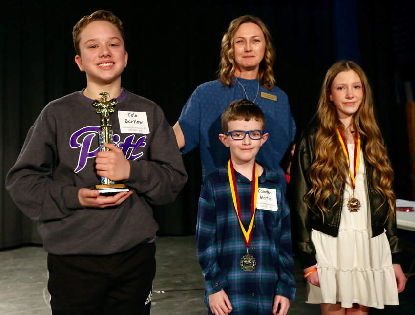 Crawford County Spelling Bee&rsquo;s top finishers were, from left, Cole Bartlow (first, Pittsburg Community Middle School), Camden Martin (second/alternate, George Nettels Elementary School), and Eastin Lofts (third, Northeast Junior High) alongside pronouncer Becky Oplotnik.