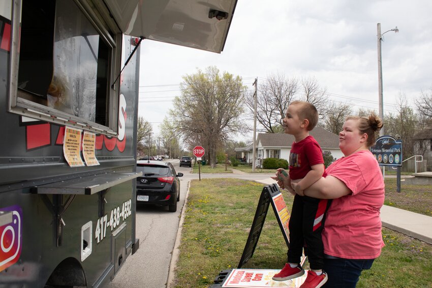 Chelsie Welborn holds up Grayson Welborn outside of the Ghetto Tacos truck April 1 parked by Veterans Memorial Park in Girard.  A different food truck will be featured in the park every first Tuesday of the month.