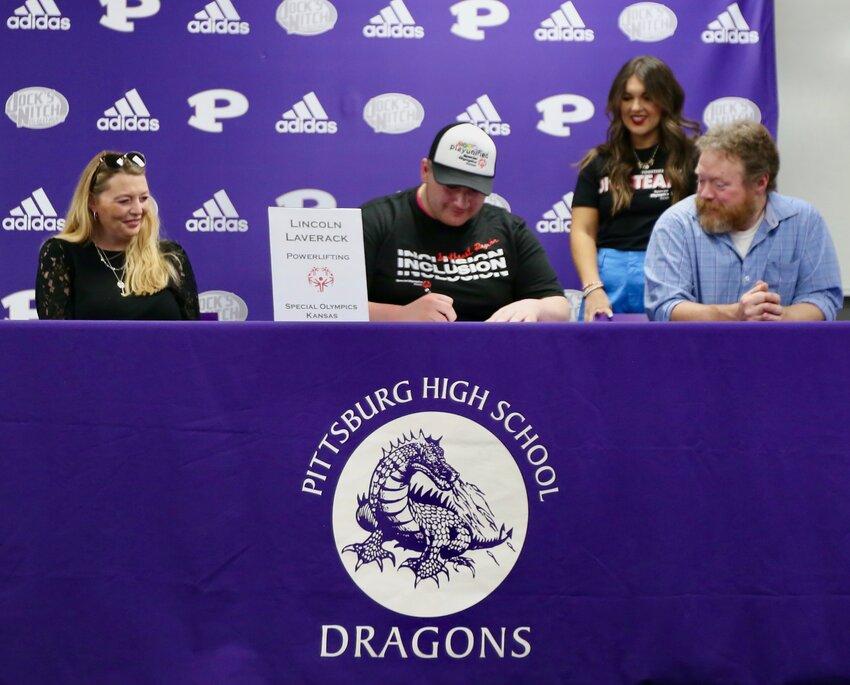 Pittsburg High School senior Lincoln Laverack signs his letter of intent to powerlift for the New Hope Bulldogs of Pittsburg Wednesday afternoon, sitting alongside his mother Julie and father Alec as well as Special Olympics Kansas Southeast Region Director Olivia Ryan.