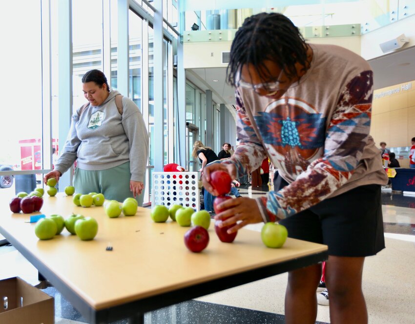 Pittsburg State University student Stirling Luckey competes against a friend in an apple stacking competition during Wednesday&rsquo;s celebration of Apple Day at the Bicknell Family Center of the Arts. Lucky was also the recipient of a $500 scholarship won in a drawing during Apple Day festivities.