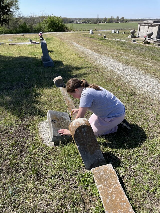 Southeast seventh-grader Chloe Clark cleans a headstone at the Cherokee Cemetery during a Day of Service on Monday.
