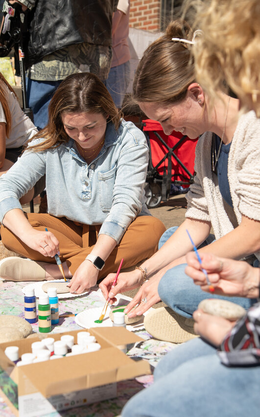 Morgan Kinsey, left, and Ashlee Wilber paint rocks to be placed in Pittsburg State University&rsquo;s new Native Garden. The garden, which fills two large planters on the west side of Heckert-Wells Hall, has been planted with nine species of plants native to the region. Kinsey and Wilber were joined by a number of staff, Tuesday, in celebration of Earth Day. Jordan Hayworth, president of Students for Sustainability, said her organization will be responsible for maintaining the garden on a regular basis.