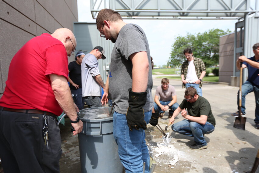 Investment Casting Institute instructor Russ Rosmait, very left, assists a course participant with dipping a scalding hot cast into cold water while several other participants behind break the mold off the cast during this year&rsquo;s annual course at the Crossland Technology Center.