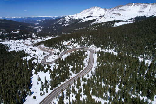 A road winds through the snow-covered Rocky Mountains at Hoosier Pass as seen from the air, Monday, April 18, 2022, near Blue River, Colo. Some drought-prone communities in the U.S. West are mapping snow by air to refine their water forecasts. It's one way water managers are adjusting as climate change disrupts weather patterns and makes current forecasting methods less reliable. (AP Photo/Brittany Peterson)