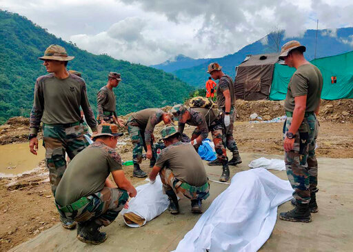 Soldiers wrap bodies of victims of a mudslide in Noney, northeastern Manipur state, India, Friday, July 1, 2022. Rescuers found more bodies Friday as they resumed searching for dozens of missing after a mudslide triggered by weeks of heavy downpours killed at least 19 people at a railroad construction site in India's northeast, officials said. (AP Photo/Agui Kamei)