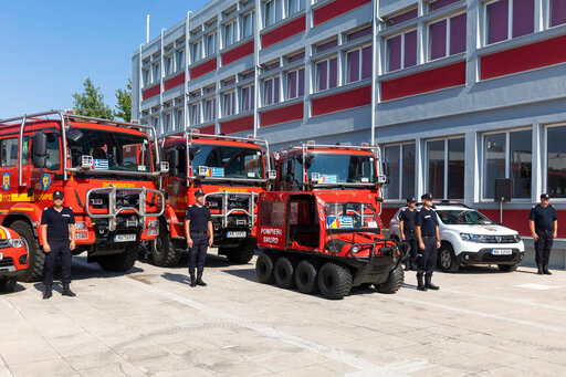 Romanian firefighters stand in front of fire engines during a ceremony, in Athens, on Saturday, July 2, 2022. Twenty eight Romanian firefighters, the first of more than 200 firefighters from other European countries that will help their Greek colleagues in fighting wildfires, were welcomed by Climate Crisis and Civil Protection Minister Christos Stylianides and the leadership of Greece's Fire Service. (AP Photo/Yorgos Karahalis)