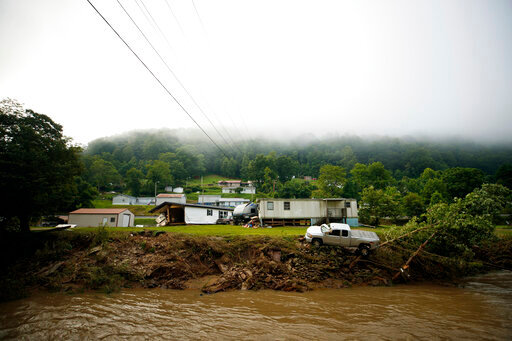 A truck sits on the edge over a river, Thursday, July 14, 2022 in Whitewood, Va., after being swept away in a flash flood . Virginia Gov. Glenn Youngkin declared a state of emergency to aid in the rescue and recovery efforts from Tuesday's floodwaters. (AP Photo/Michael Clubb)