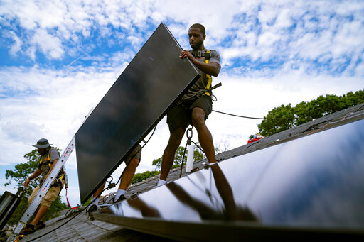 FILE - Employees of NY State Solar, a residential and commercial photovoltaic systems company, install an array of solar panels on a roof, Aug. 11, 2022, in the Long Island hamlet of Massapequa, N.Y. Massive incentives for clean energy in the U.S. law signed Tuesday, Aug. 16, by President Joe Biden should reduce future global warming “not a lot, but not insignificantly either,” according to a climate scientist who led an independent analysis of the climate package.  (AP Photo/John Minchillo, File)