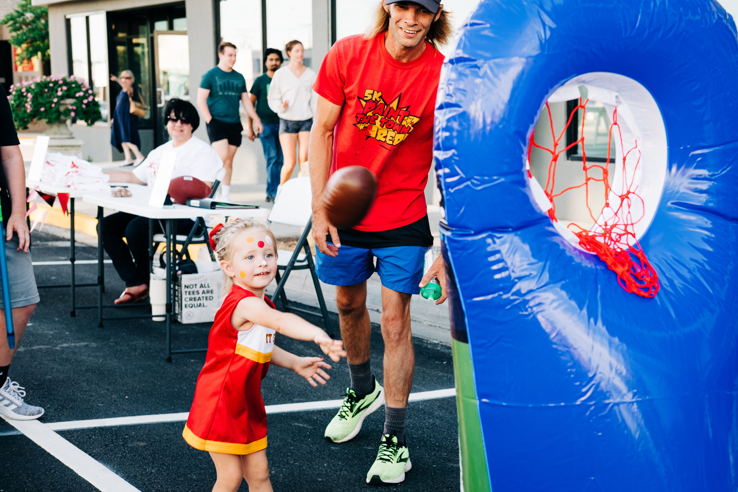 2-year-old Kelce Phillips throws the ball into the net on Broadway during the Paint the Town Red Block Party on Wednesday.