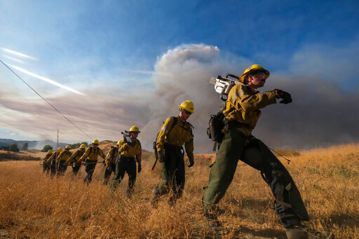 Firefighters walk in a line during a wildfire in Castaic, Calif. on Wednesday, Aug. 31, 2022. (AP Photo/Ringo H.W. Chiu)