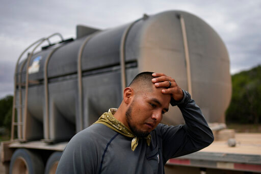 Garnett Querta wipes sweat from his head while hauling water on the Hualapai reservation Monday, Aug. 15, 2022, near Peach Springs, Ariz. The water pulled from the ground here will be piped dozens of miles across the rugged landscape to serve the roughly 600,000 tourists a year who visit the Grand Canyon on the Hualapai reservation in northwestern Arizona — an operation that's the tribe's main source of revenue. (AP Photo/John Locher)
