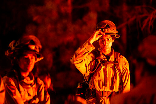 Firefighter Gabriel Beltran adjusts his helmet during an overnight shift battling the Mosquito Fire in Placer County, Calif., on Tuesday, Sept. 13, 2022. (AP Photo/Noah Berger)