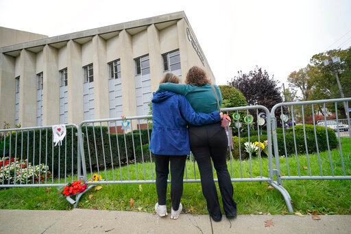 FILE - Two women pause along a fence outside the dormant landmark Tree of Life synagogue in Pittsburgh's Squirrel Hill neighborhood on Wednesday, Oct. 27, 2021.   The long-delayed capital murder trial of Robert Bowers in the 2018 Pittsburgh synagogue massacre will begin in April, 2023 a federal judge has ruled. (AP Photo/Gene J. Puskar, File)