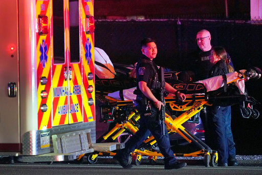 A law enforcement officer walks past an EMS crew on the scene at Kennywood Park, an amusement park in West Mifflin, Pa., early Sunday, Sept 25, 2022. Pennsylvania police and first responders have descended on the amusement park southeast of Pittsburgh following reports of shots fired inside the attraction, which was kicking off a Halloween-themed festival. (AP Photo/Gene J. Puskar)