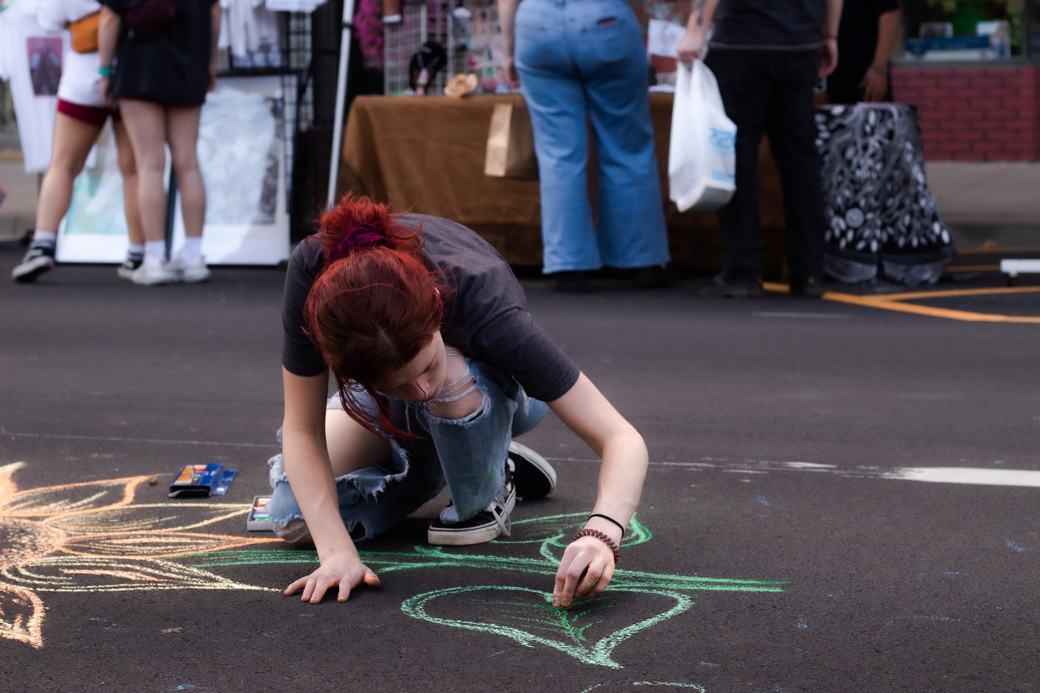 Pittsburg resident Emily Taffner draws a sunflower with chalk on the pavement in the middle of the Pittsburg ArtWalk. Taffner said she had spent about half an hour drawing the flower. MORIE PRICE / THE MORNING SUN