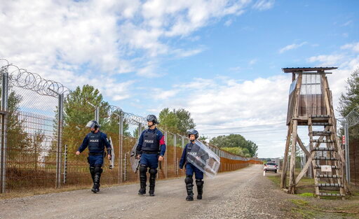 FILE - Operational police officers walk along the service route of Hungary's border with Serbia near Roszke, Southern Hungary, Wednesday, Sept. 28, 2022. The leaders of Hungary, Austria and Serbia met Monday in Budapest to find solutions on how to stem the recently increasing number of migrants arriving in Europe. (Tibor Rosta/MTI via AP, File)