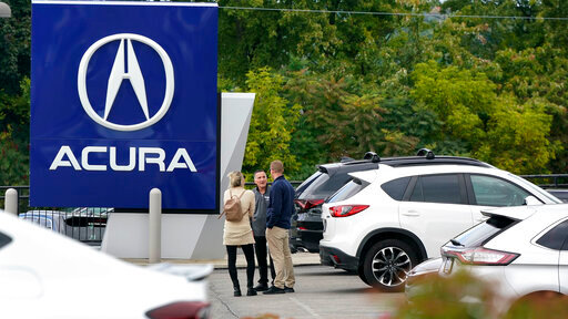 FILE - A salesman talks with customers in an Acura dealership lot in Wexford, Pa., on Sept. 29, 2022. New vehicle sales in the U.S. are expected to have fallen slightly in the third quarter, even with improvement in September. But there are warning signs that consumers' appetite for expensive new cars, trucks and SUVs may be waning. (AP Photo/Gene J. Puskar, File)