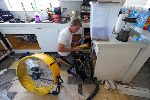 Jordan Cromer cleans water-logged items at his home, Tuesday, Oct. 4, 2022, in North Port, Fla. Residents along Florida's west coast are cleaning up damage after Hurricane Ian make landfall the week before. (AP Photo/Chris O'Meara)