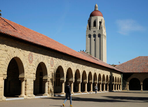 FILE- People walk on the Stanford University campus beneath Hoover Tower in Stanford, Calif., on March 14, 2019. Stanford University has apologized for limiting the admission of Jewish students in the 1950s after a task force commissioned by the school earlier this year found records that show university officials excluded Jewish students for years. (AP Photo/Ben Margot, File)