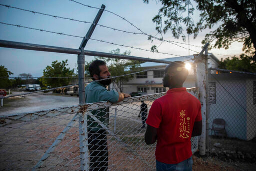 FILE - A manager at the Christian Aid Ministries headquarters, left, speaks with a worker at the door of the center in Titanyen, north of Port-au-Prince, Haiti, Sunday, Nov. 21, 2021. A year after 17 North American missionaries were kidnapped in Haiti, beginning a two-month ordeal before they ultimately went free, Christian Aid Ministries, the agency that sent them hasn't made a permanent return, and several other international groups have also scaled back their work there. (AP Photo/Odelyn Joseph)