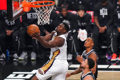 New Orleans Pelicans' Zion Williamson, left, drives past Brooklyn Nets' Nic Claxton, top right, and Ben Simmons during the first half of an NBA basketball game Wednesday, Oct. 19, 2022 in New York. (AP Photo/Frank Franklin II)
