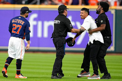 Security remove a fan on the field in between the eighth and ninth innings in Game 2 of baseball's American League Championship Series between the Houston Astros and the New York Yankees, Thursday, Oct. 20, 2022, in Houston. (AP Photo/Kevin M. Cox)