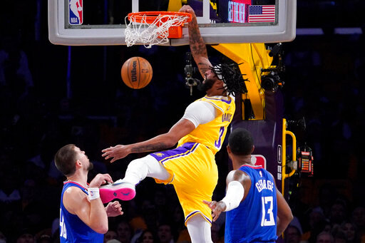 Los Angeles Lakers forward Anthony Davis, center, dunks as Los Angeles Clippers center Ivica Zubac, left, and guard Paul George defend during the first half of an NBA basketball game Thursday, Oct. 20, 2022, in Los Angeles. (AP Photo/Mark J. Terrill)