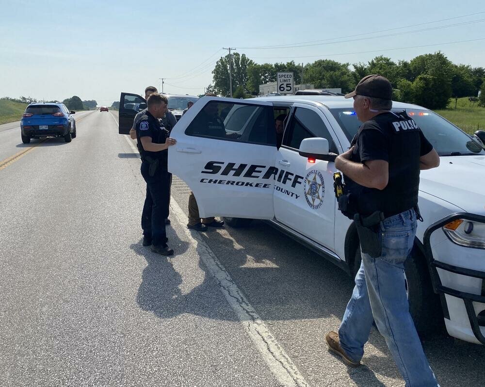 Law enforcement officers speak to Hunter Hayes-Bebee, 24, of Galena, in the back of a squad car Thursday, May 25 after Bebee led police on a pursuit through Cherokee County.
